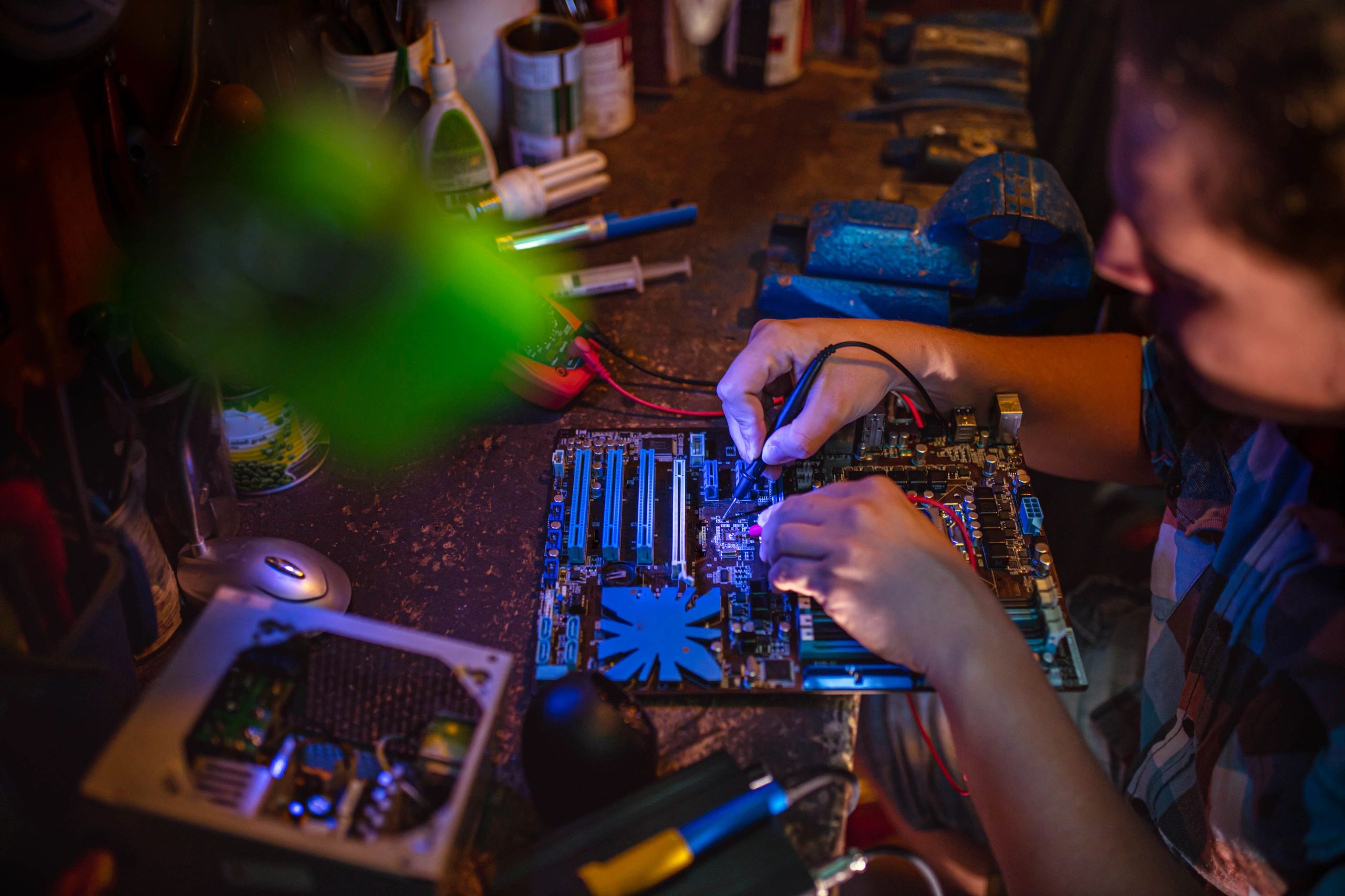 Technician testing a PC motherboard with a multimeter